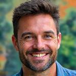 Portrait professionnel souriant d'Arthur Dumas, Travel Designer, avec un arrière-plan flou de l'Amérique du Sud tropicale